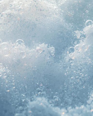 Photo en gros plan d'eau avec des bulles et de la mousse pour représenter le phénomène de primage (quand de l'oxygène se mélange à l'eau